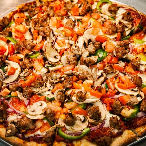 A whole pizza with sausage, mushrooms, green peppers, red onions, and diced tomatoes.
